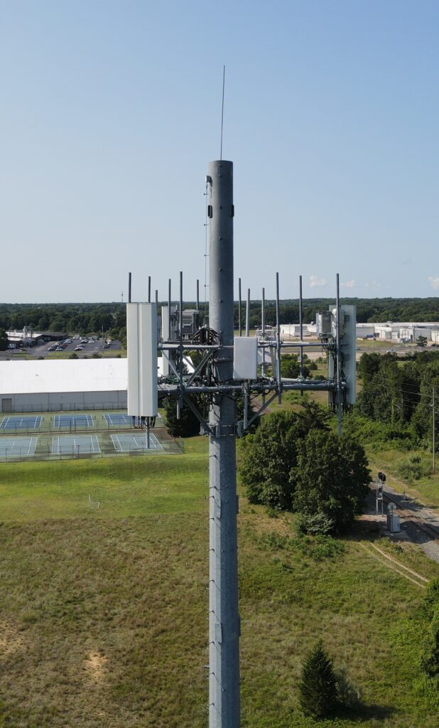 Upper portion of a cellular tower shown with several antenna around the pole